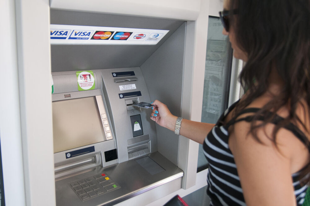 Devojka stavlja platnu karticu u bankomat 