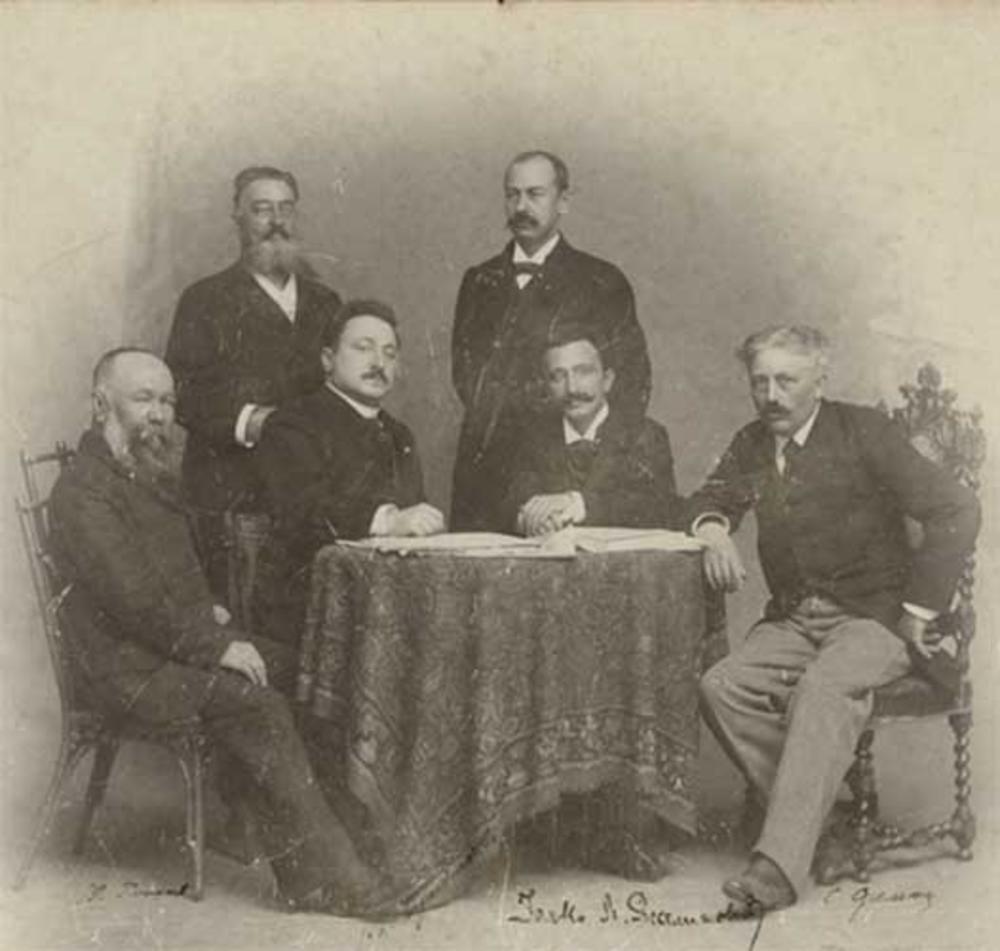 Stevan Sremac za stolom desno, u društvu Milovana Glišića, Branislava Nušića, Janka Veselinivića, Aleksandra Sumbatova i Dragomira Brzaka