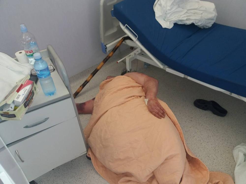 Nesrećni čovek leži na podu bolnice         
