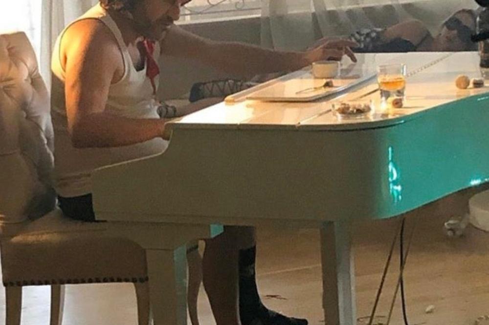 ACA LUKAS U GAĆAMA I SILEDŽIJKI ZA KLAVIROM, RASPARENE ČARAPE NA NOGAMA: A oko njega haos, prazne flaše i pune čaše