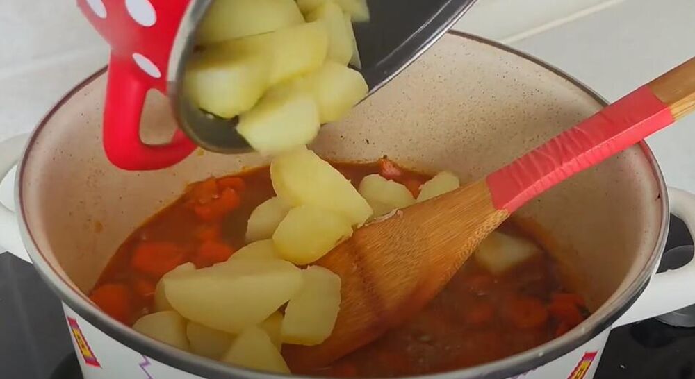 Stavljanje krompira u šerpu sa crnim lukom i šargarepom