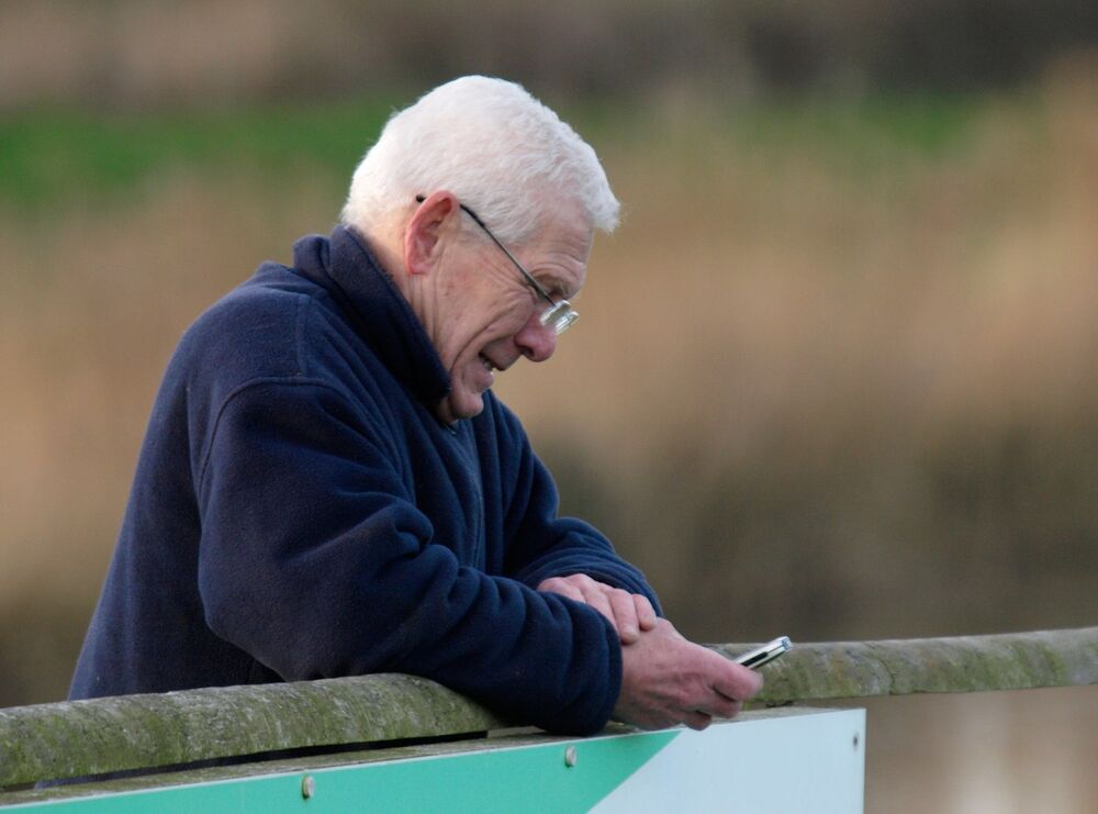 Jedan penzioner stoji i gleda u telefon