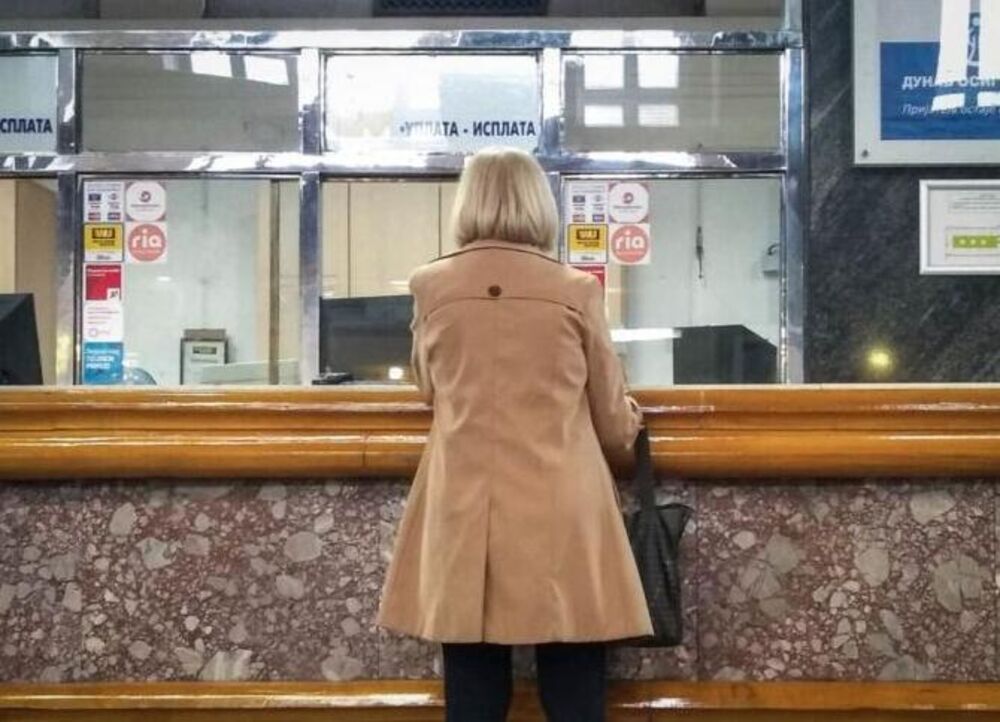Žena u pošti stoji na šalteru